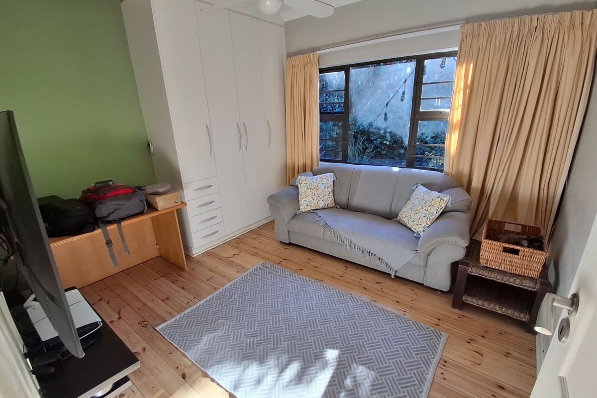 A bedroom featuring polished timber flooring, a built-in wardrobe, and a ceiling fan, offering a functional space with natural light.