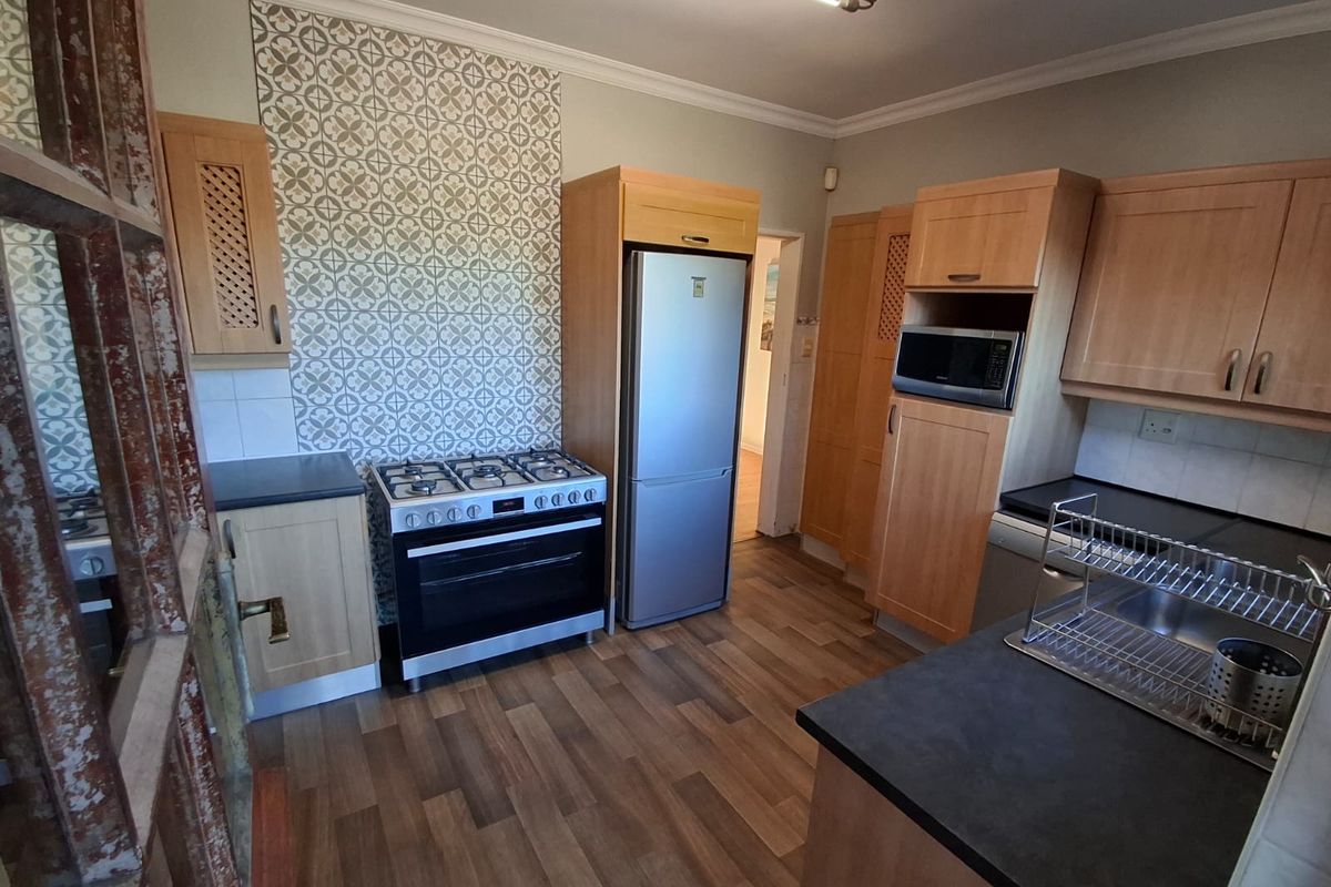 Functional kitchen featuring light wood cabinetry, gas stove, built-in microwave, and a decorative tiled splashback with durable laminate countertops.