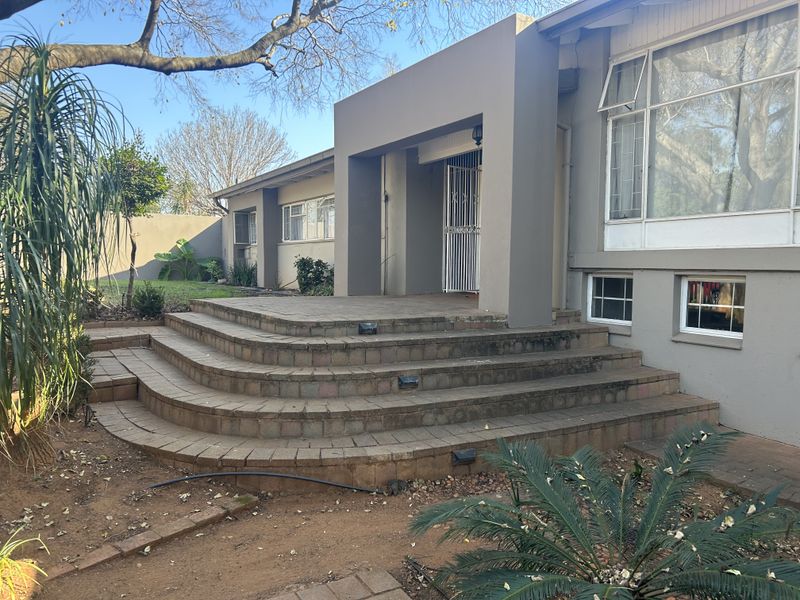 Front entrance featuring a set of curved brick steps leading to a recessed doorway with a security gate and large windows.