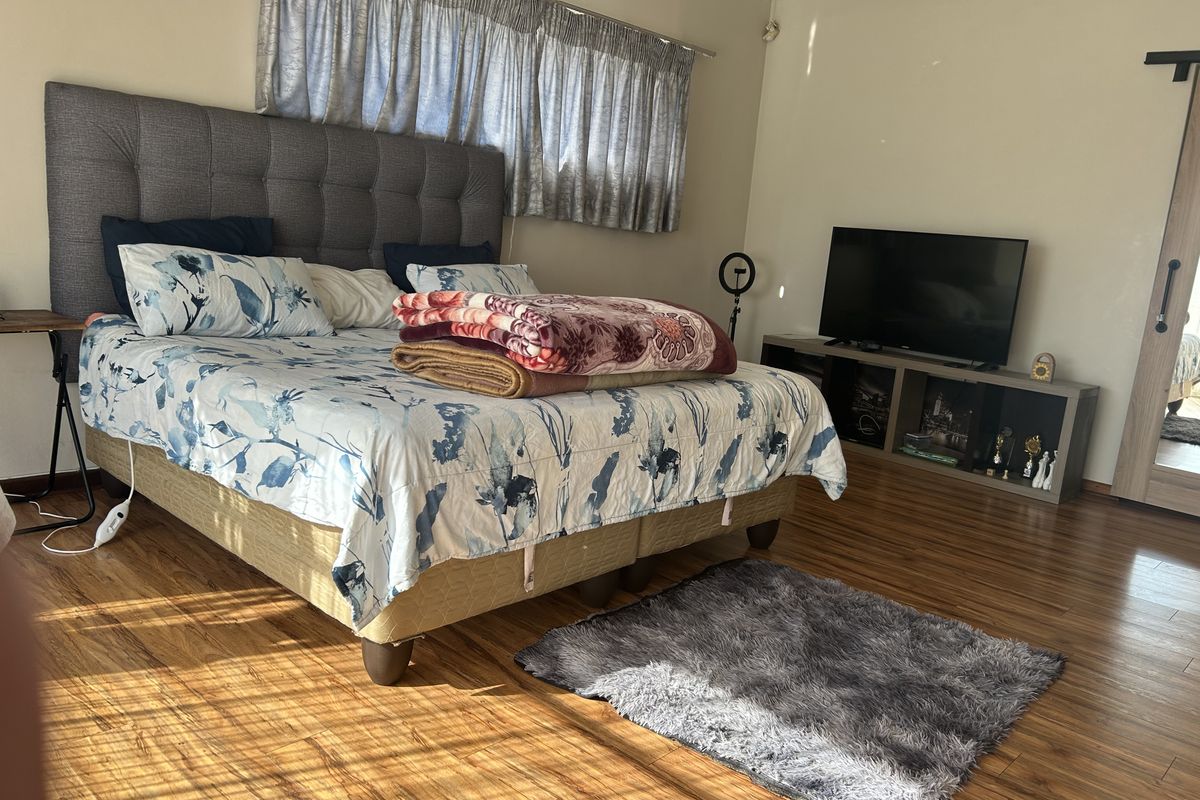 A well-maintained bedroom featuring warm-toned laminate flooring and a modern sliding barn door, providing a clean and functional living space.