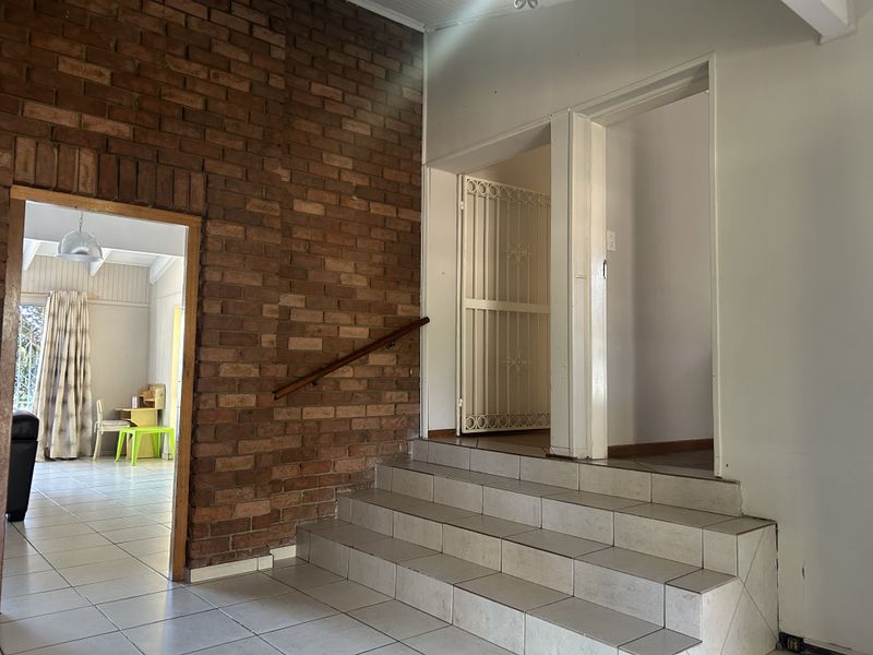 Entrance area featuring a prominent exposed brick wall, tiled staircase with a wooden handrail, and access to adjacent living spaces.
