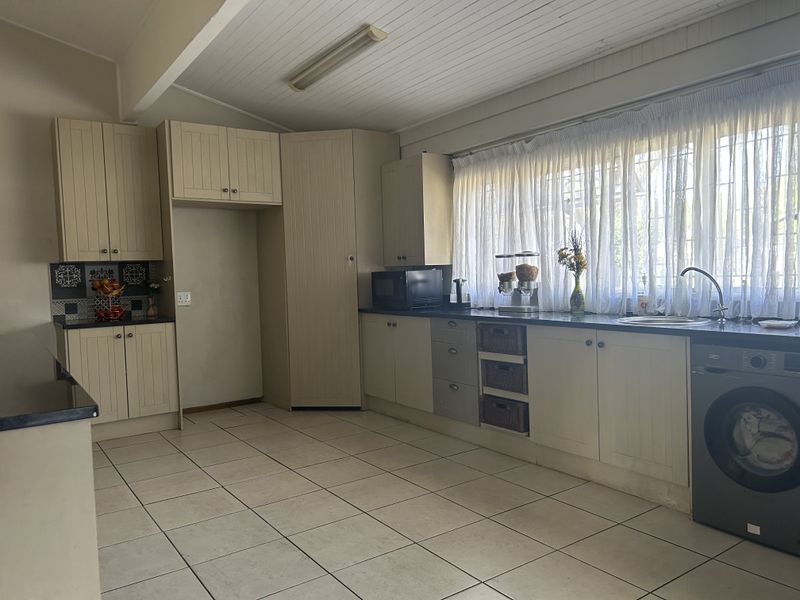 A functional kitchen featuring ample built-in cabinetry, tiled flooring, and a integrated washing machine, offering a practical layout with potential for modern updates.