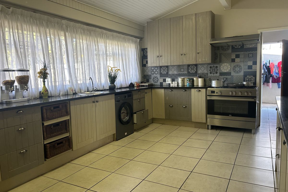 A functional kitchen featuring built-in cabinetry, granite countertops, a stainless steel oven with extractor fan, and decorative tiled backsplash.