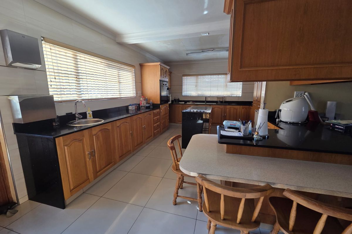 Spacious kitchen featuring extensive wooden cabinetry, granite countertops, a central island, and tiled flooring, offering a functional layout with ample storage space.