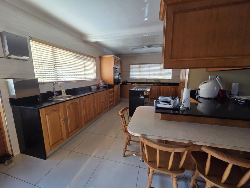 Spacious kitchen featuring extensive wooden cabinetry, granite countertops, a central island, and tiled flooring, offering a functional layout with ample storage space.