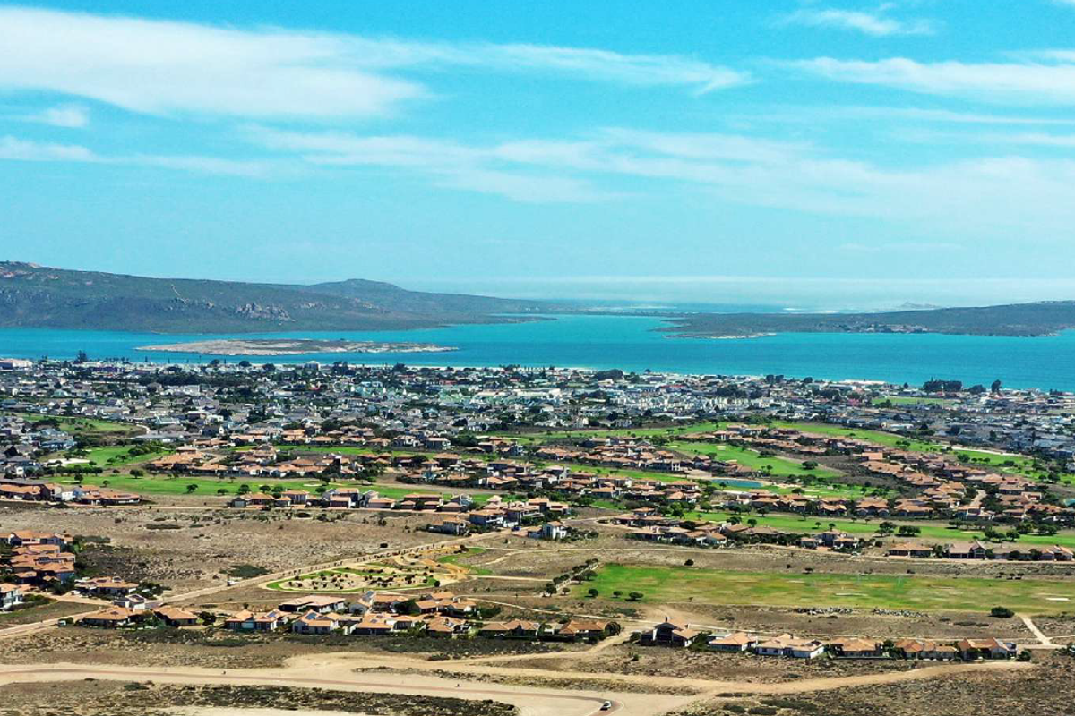 An elevated aerial view showcasing the coastal landscape, residential estate, and surrounding natural environment.