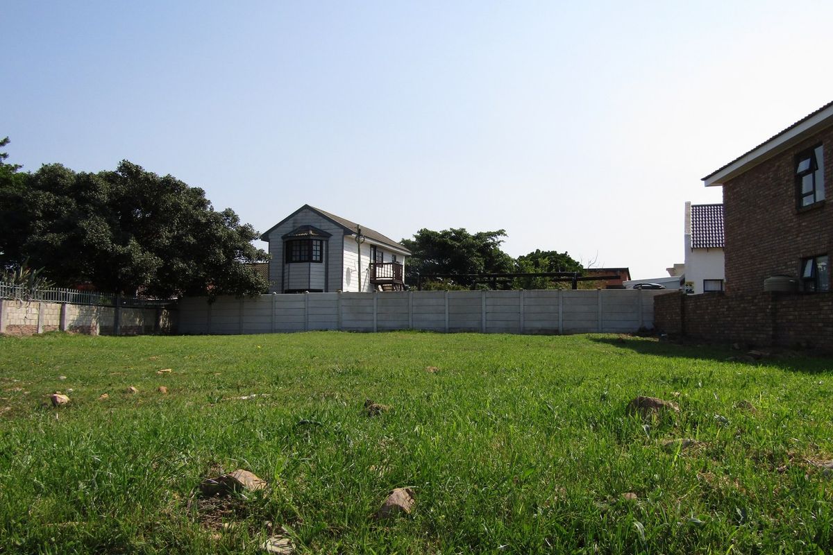 A vacant residential plot featuring a grassed area enclosed by precast concrete and brick boundary walls.