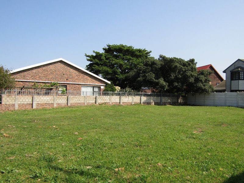 A vacant residential plot featuring a level grassed area enclosed by a combination of brick and precast concrete boundary walls with security fencing.
