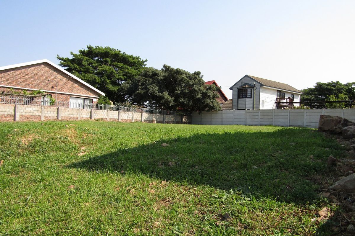 A view of a vacant residential plot featuring a grass lawn and enclosed by precast concrete boundary walls.