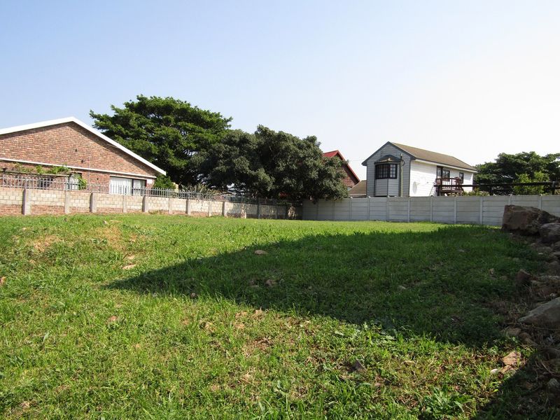 A view of a vacant residential plot featuring a grass lawn and enclosed by precast concrete boundary walls.