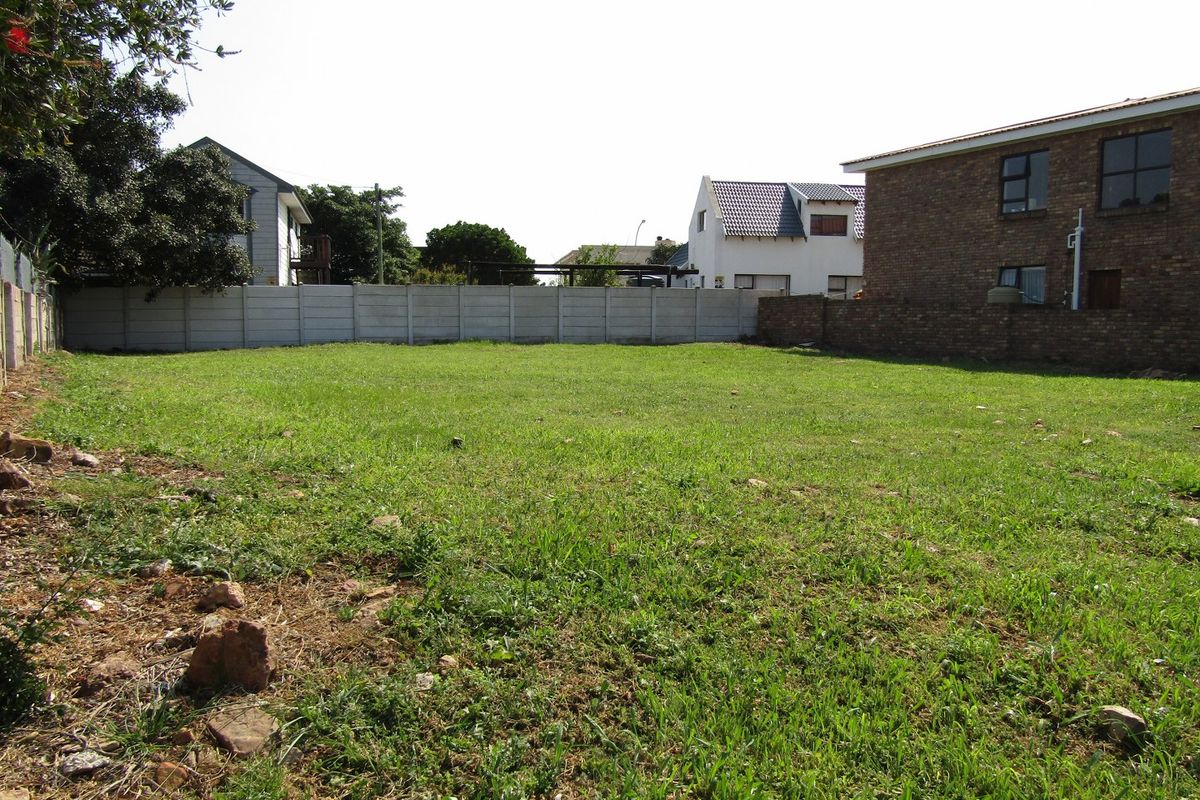 A vacant residential plot featuring a grass lawn enclosed by precast concrete and brick boundary walls in a established neighborhood.