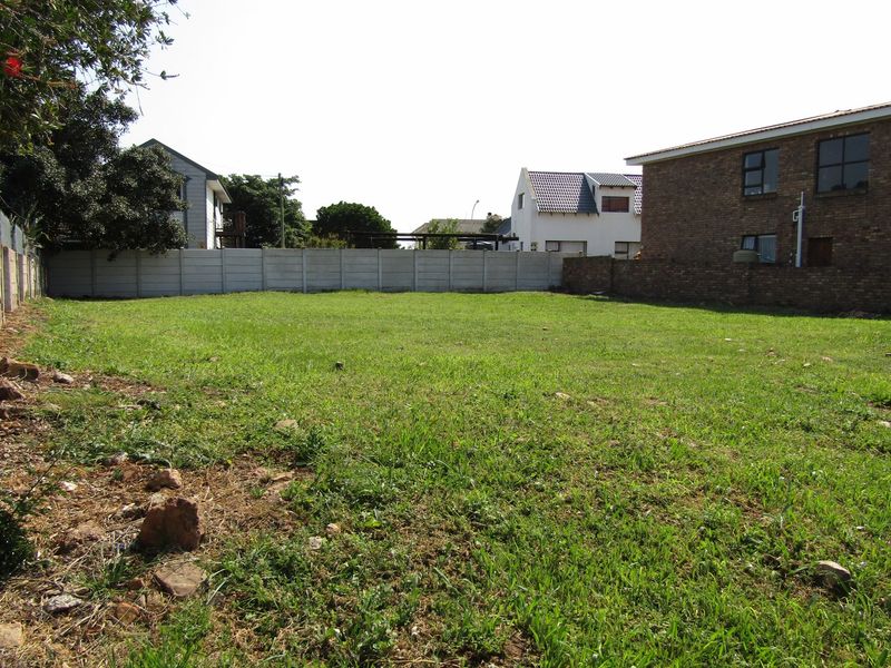 A vacant residential plot featuring a grass lawn enclosed by precast concrete and brick boundary walls in a established neighborhood.