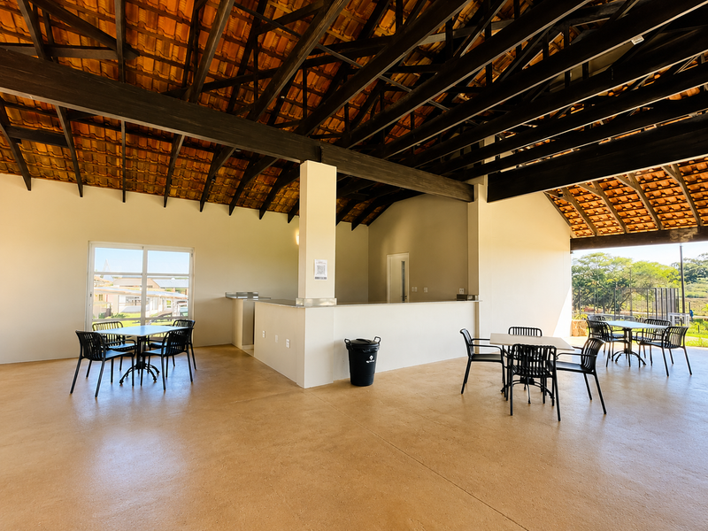 Spacious clubhouse area featuring high vaulted ceilings with exposed timber trusses, a built-in service counter, and large sliding doors opening to the exterior.