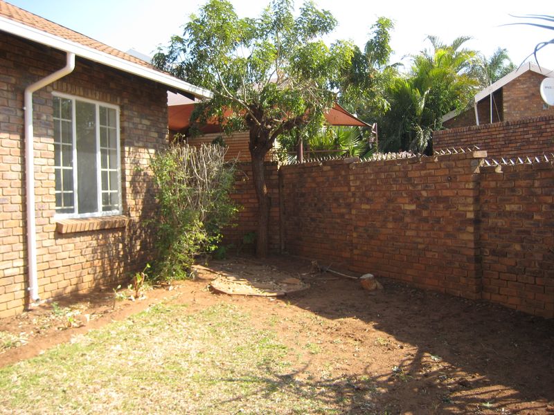 A rear garden area featuring face brick walls with security spikes and a small lawn space.