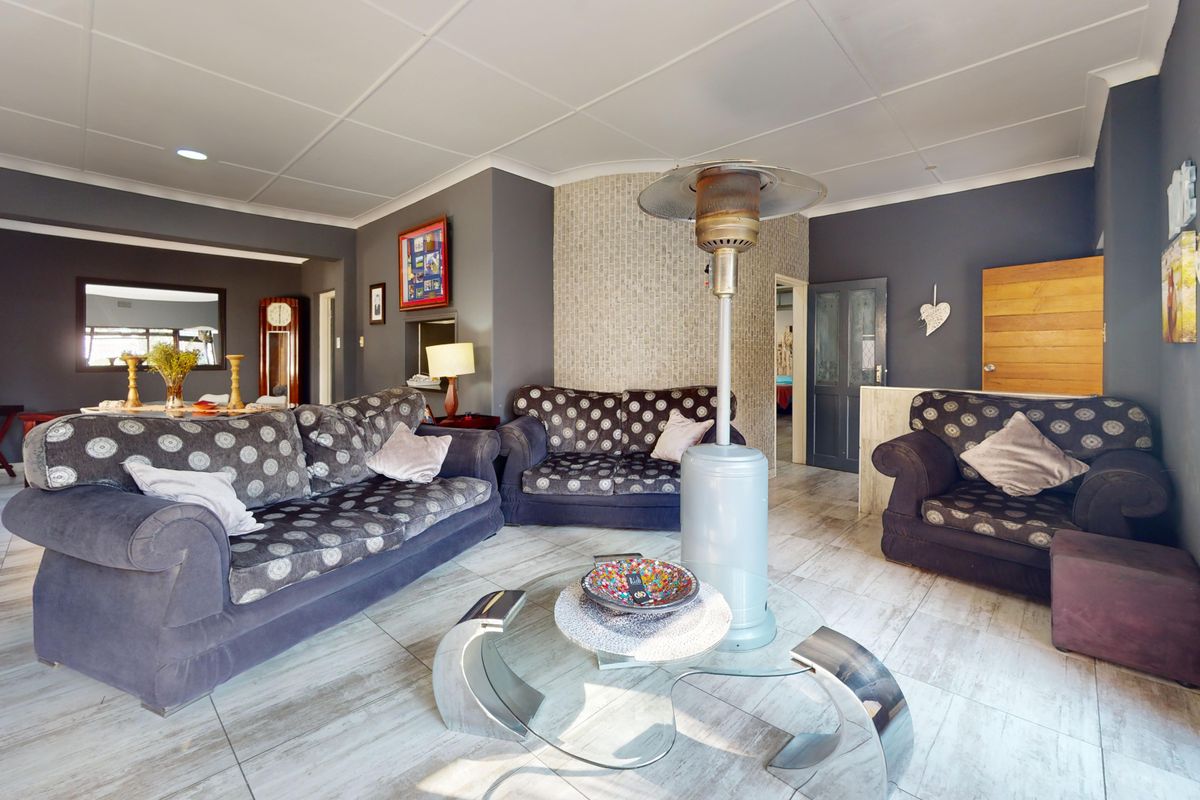 Spacious living room featuring light-toned tiled flooring, dark grey walls, and a textured feature wall, creating a contemporary living space.