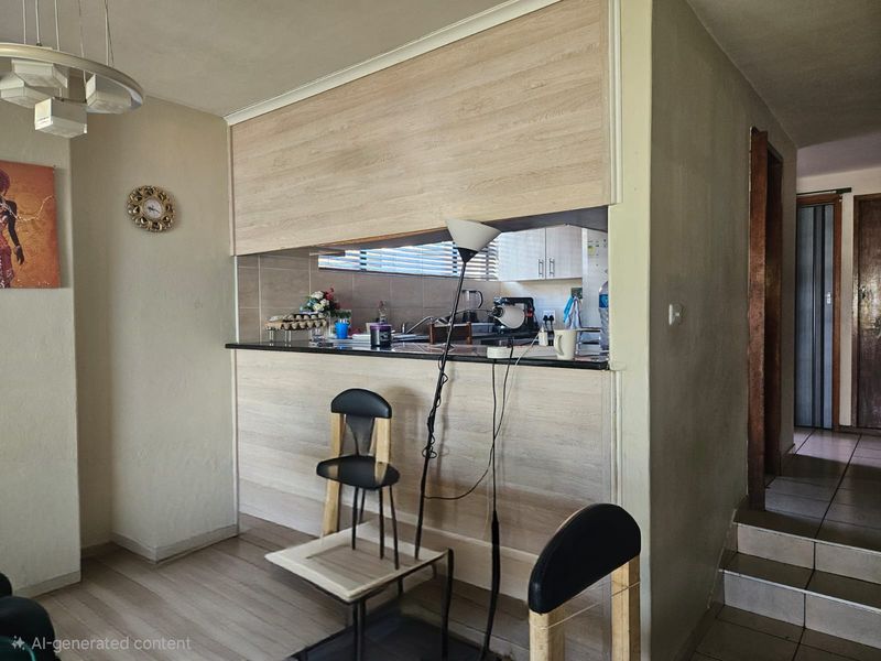 Open plan living area featuring a breakfast bar with wood-look cabinetry and a tiled backsplash, connecting to the kitchen and adjacent staircase.