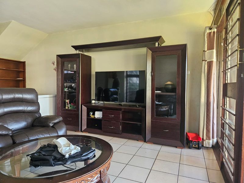 A living room featuring tiled flooring and a sliding glass door, providing access to the exterior area.