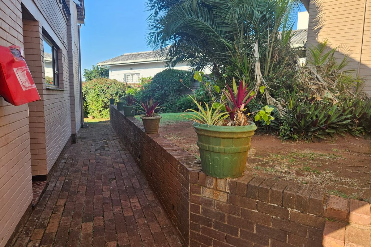 A side pathway featuring brick paving and a low brick retaining wall leading towards a rear garden area.