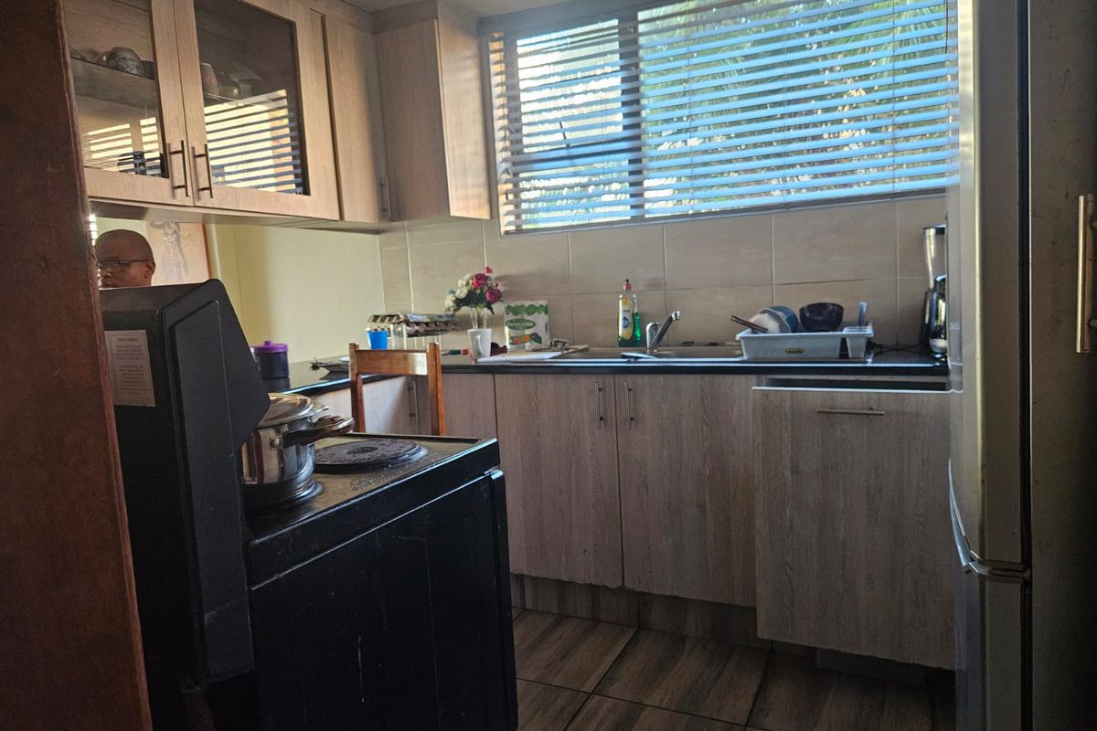 A functional kitchen featuring laminate cabinetry, stone countertops, tiled backsplash, and tiled flooring, offering a practical layout for daily meal preparation.