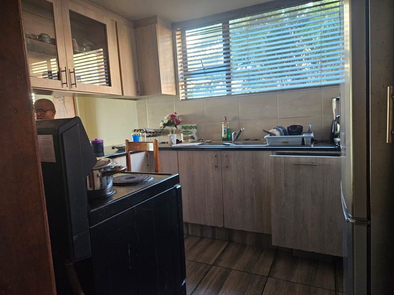 A functional kitchen featuring laminate cabinetry, stone countertops, tiled backsplash, and tiled flooring, offering a practical layout for daily meal preparation.