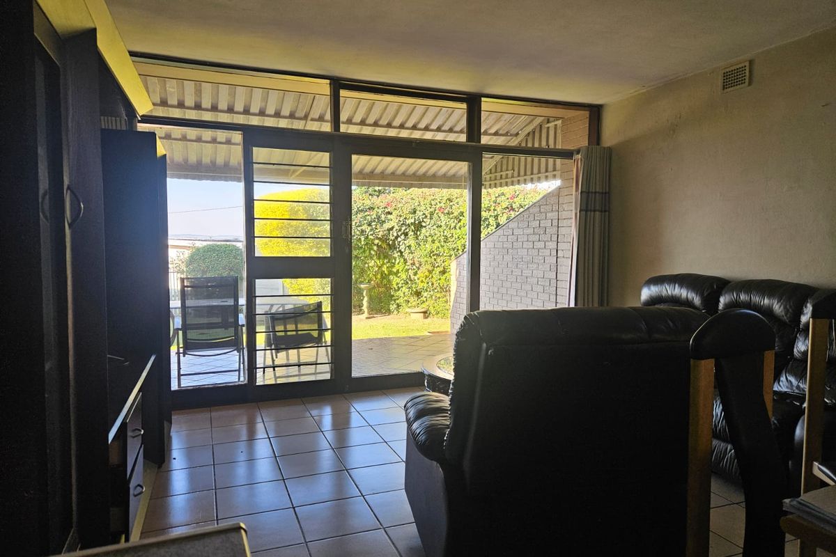 Living room featuring tiled flooring and large sliding glass doors providing direct access to a covered patio and garden area.