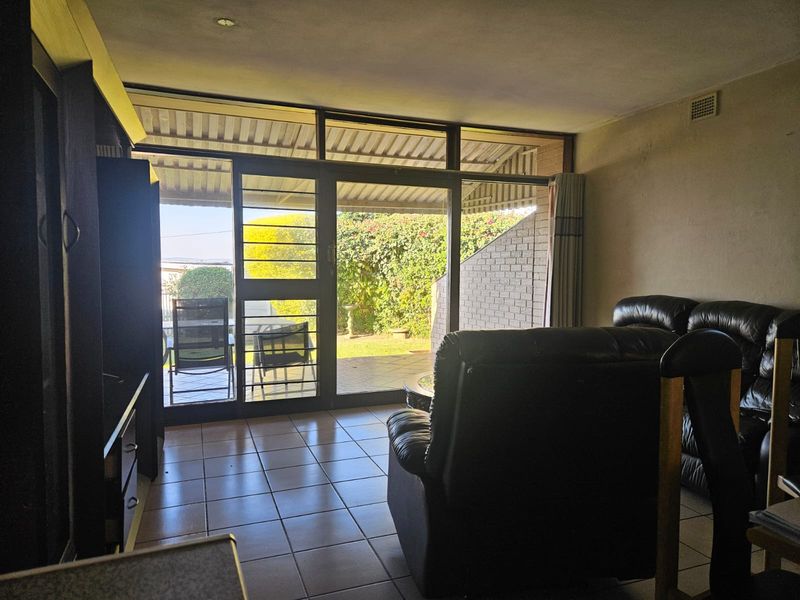 Living room featuring tiled flooring and large sliding glass doors providing direct access to a covered patio and garden area.