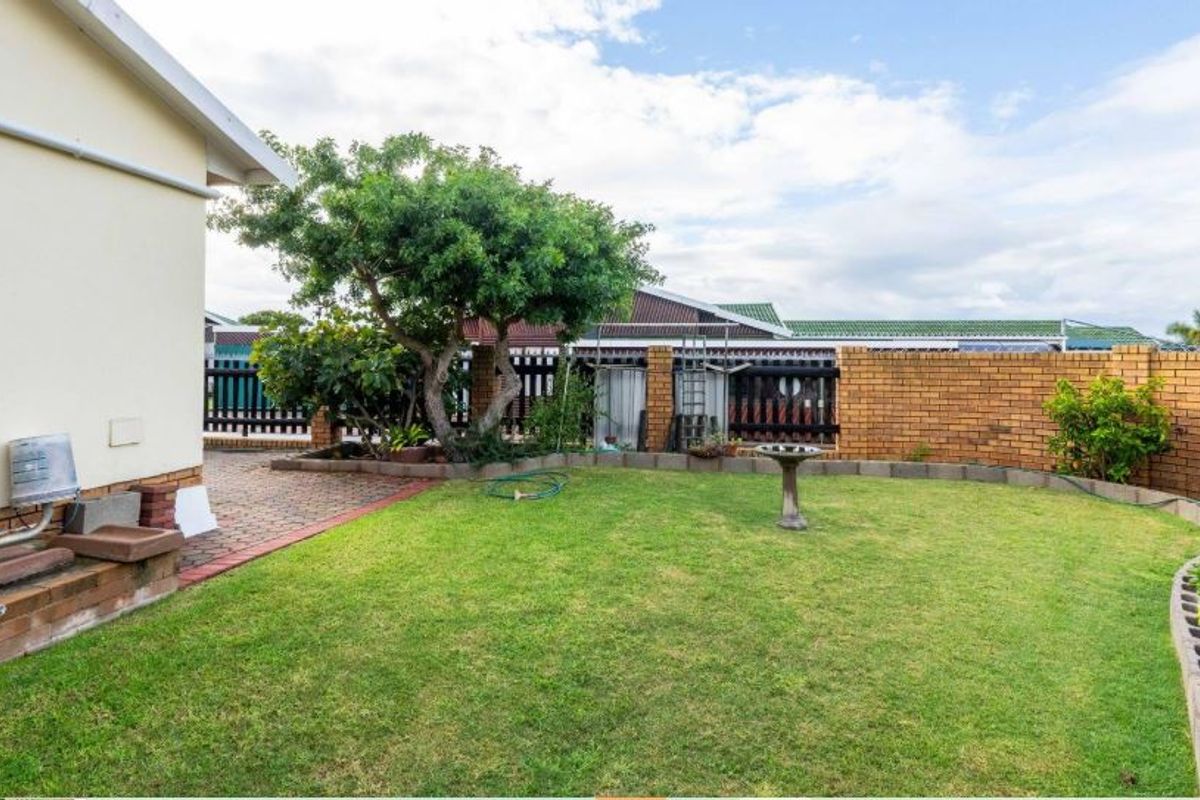 A private rear garden featuring a manicured lawn, paved patio area, and perimeter brick walling, providing a quiet outdoor space.