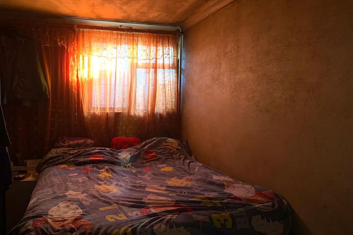 A bedroom featuring a window with natural light, requiring cosmetic updates to the walls and ceiling to improve the overall condition.