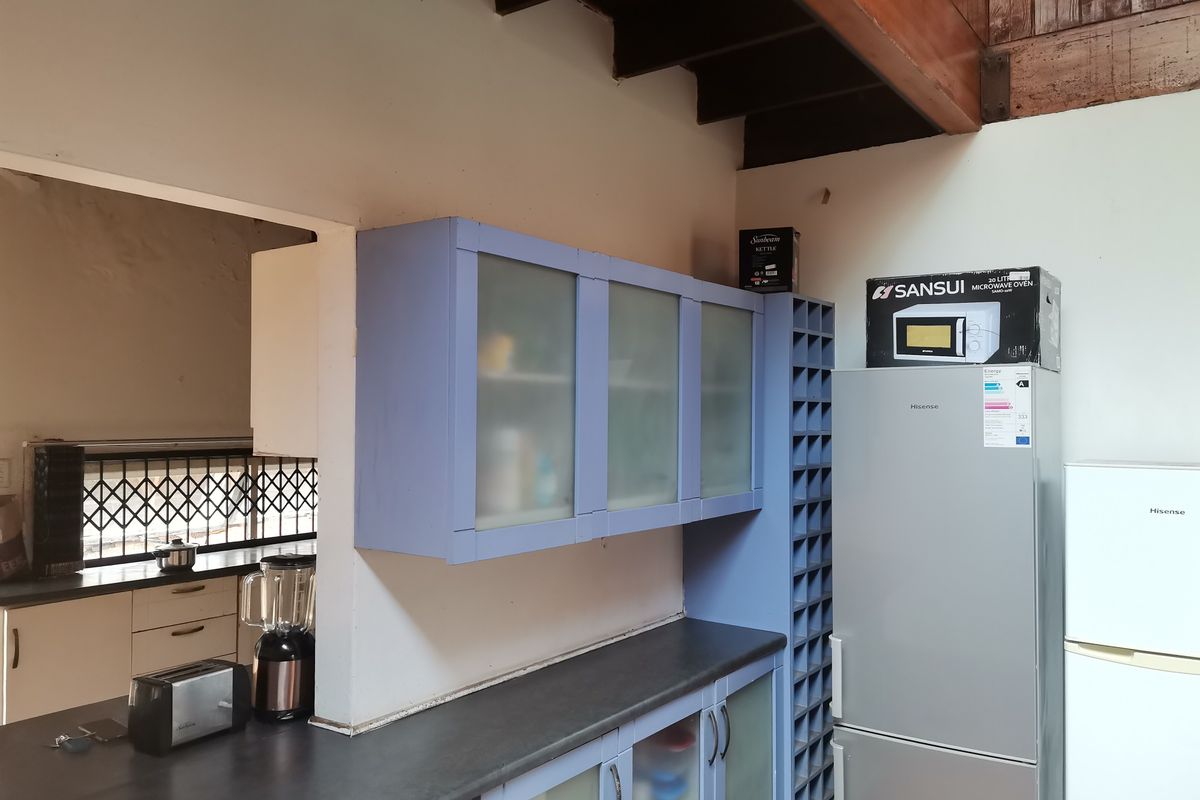 Kitchen area featuring blue cabinetry with frosted glass inserts, dark countertops, and an open-plan layout connecting to an adjacent utility space.