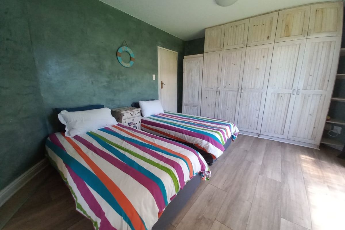A bedroom featuring wood-look flooring, a textured green accent wall, and extensive built-in wooden cabinetry for storage.