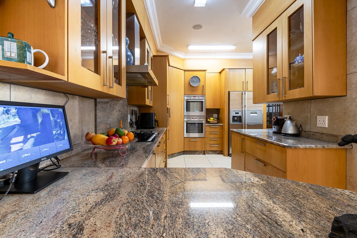 A well-appointed kitchen featuring granite countertops, extensive wooden cabinetry, and built-in appliances including a double oven and gas hob.