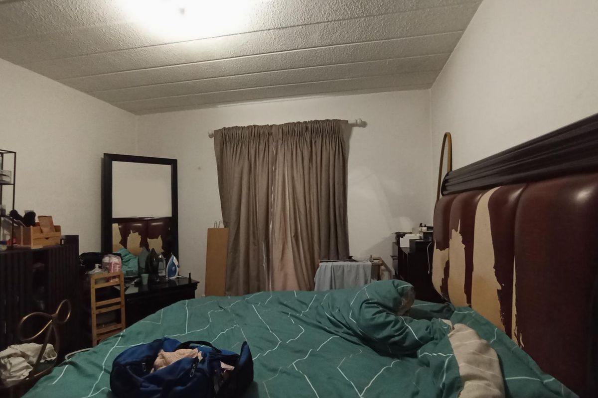 A bedroom featuring a textured ceiling and standard window treatments, currently requiring cosmetic updates to improve the overall condition of the space.