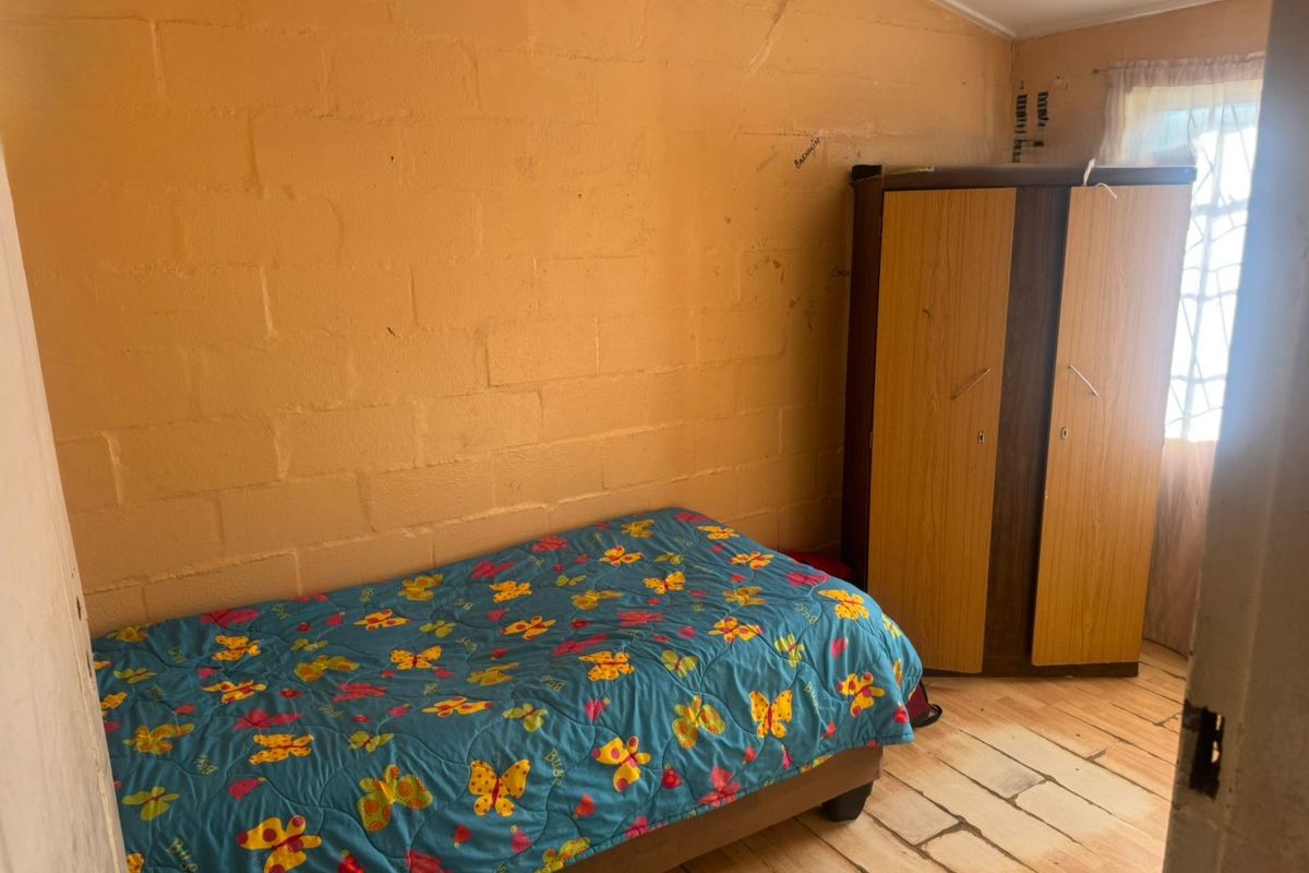A bedroom featuring exposed blockwork walls and timber flooring, requiring cosmetic updates to improve the overall aesthetic and finish.