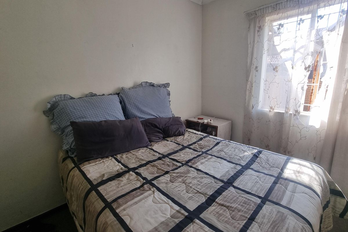 A functional bedroom featuring a window with security bars and neutral wall finishes.