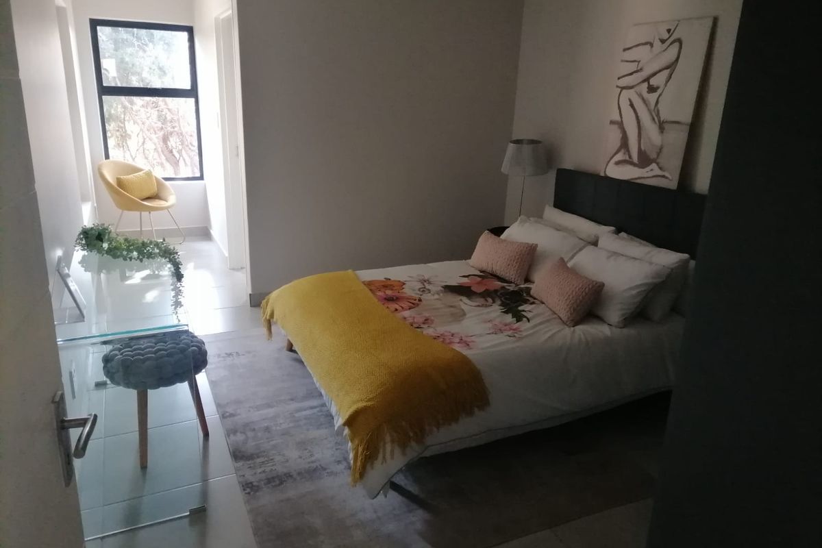 A well-lit bedroom featuring tiled flooring, neutral walls, and a large window providing natural light.