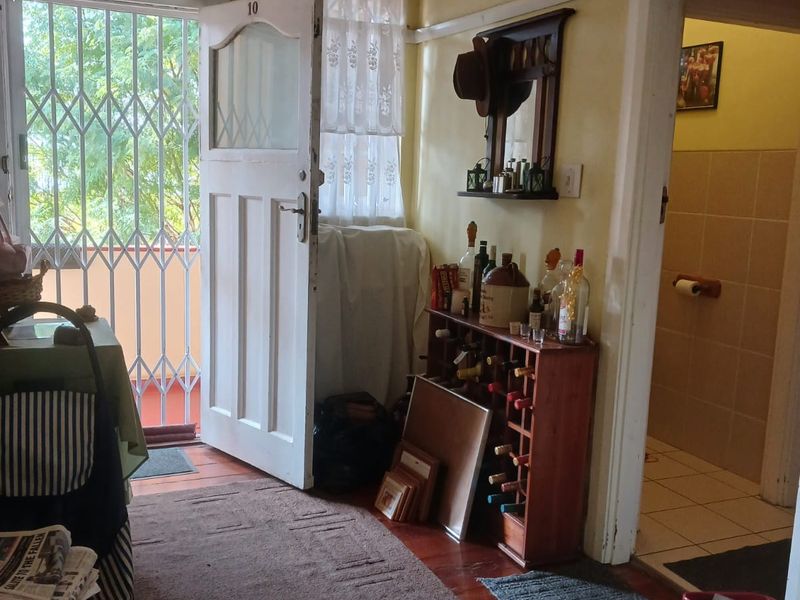 Entryway featuring timber flooring, a security gate, and direct access to the living area and adjacent bathroom.