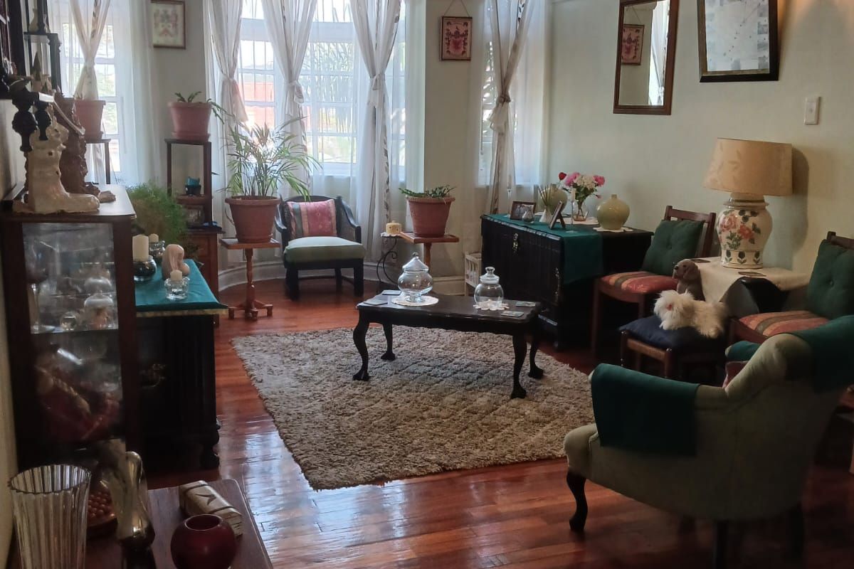 A character-filled living room featuring polished hardwood flooring, a classic bay window, and traditional picture rails, offering a warm and inviting atmosphere.