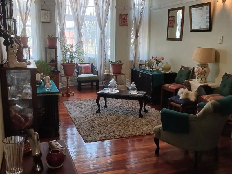 A character-filled living room featuring polished hardwood flooring, a classic bay window, and traditional picture rails, offering a warm and inviting atmosphere.