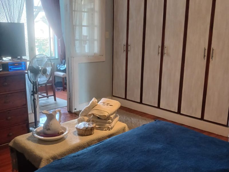 Bedroom featuring extensive built-in cupboards, hardwood flooring, and direct access to an adjoining space through classic french doors.