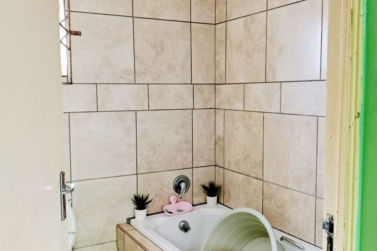 A functional bathroom featuring a built-in bathtub with neutral wall tiling and standard plumbing fixtures.