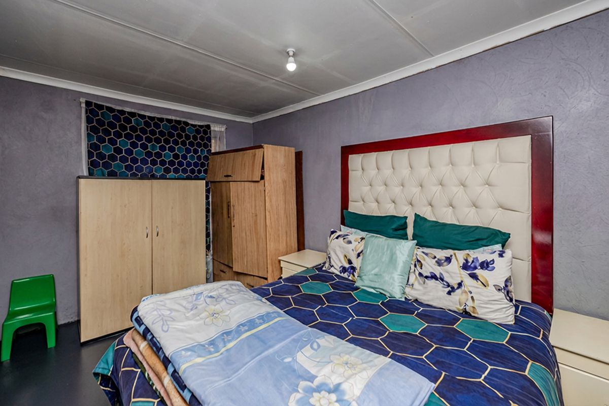 A bedroom featuring purple walls and a standard ceiling finish, providing a functional sleeping space with potential for cosmetic updates.