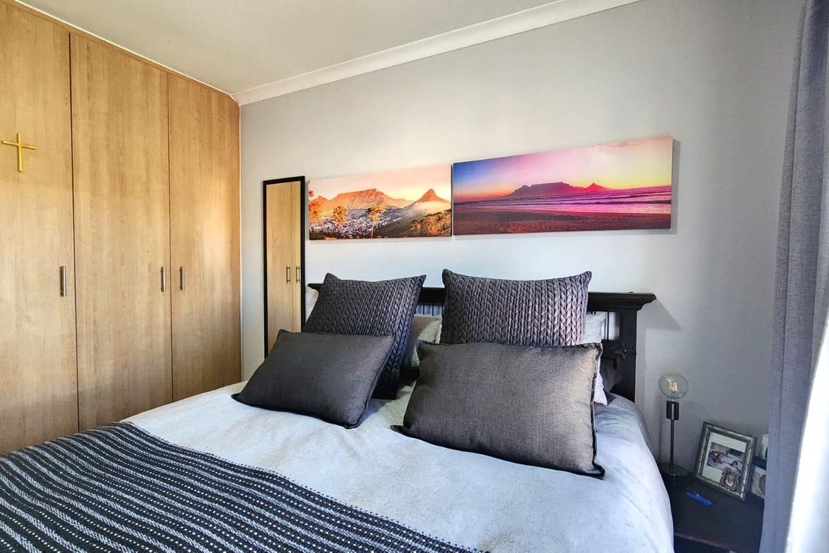A well-maintained bedroom featuring light wood-finish built-in cupboards and classic ceiling coving.