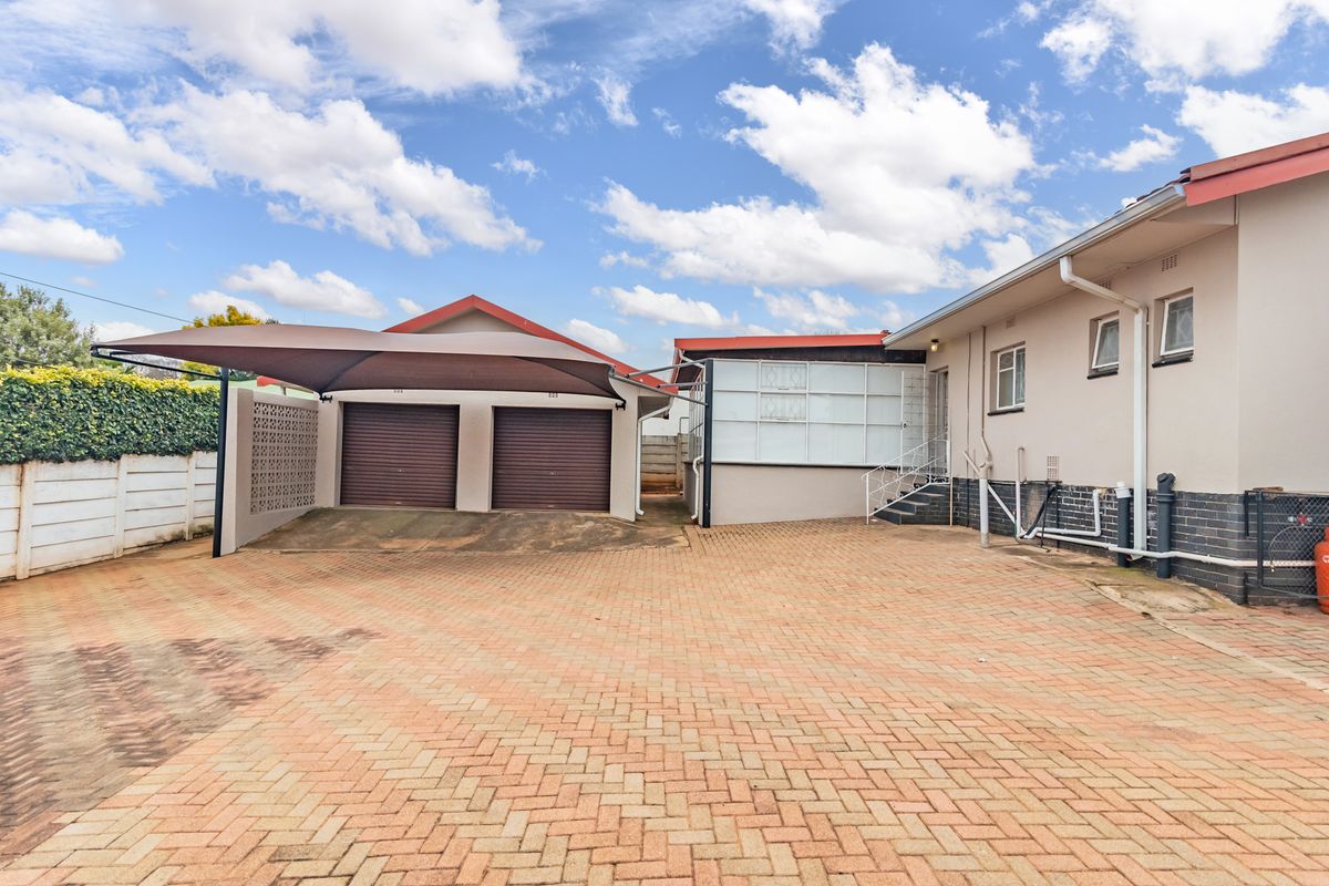Rear exterior view featuring a paved driveway, double garage with shade sail carport, and access to the main dwelling.