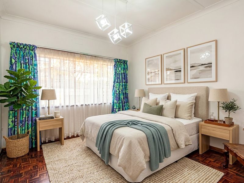 A well-maintained bedroom featuring classic parquet flooring, coved ceilings, and a large window with natural light.