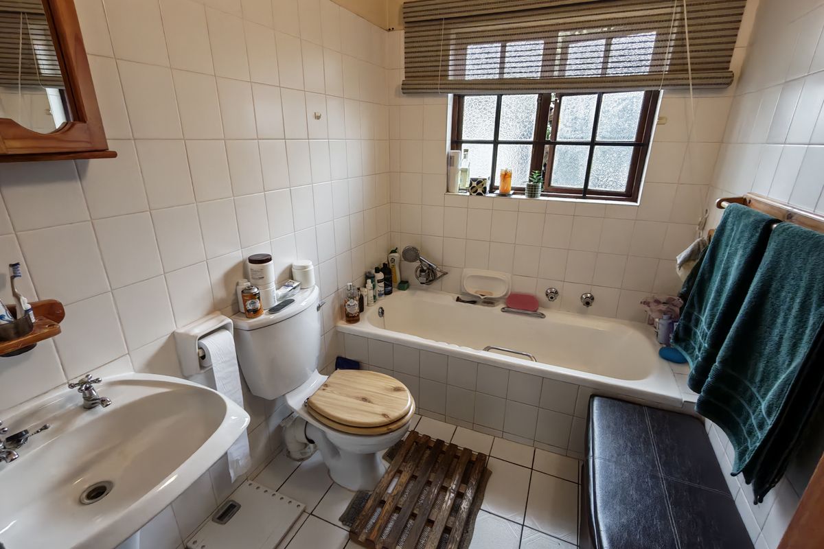 A functional bathroom featuring a pedestal basin, toilet, and a built-in bathtub with tiled wall finishes and flooring.