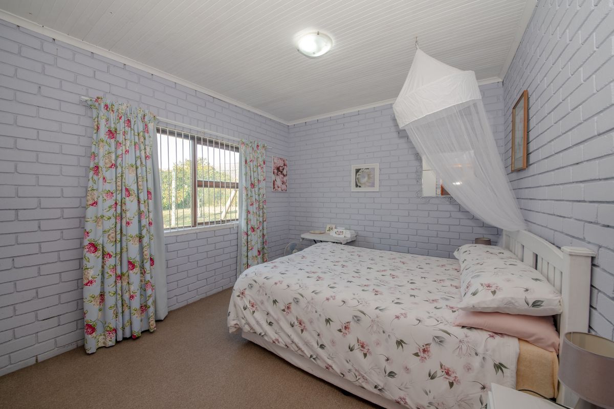 A bedroom featuring painted brick walls, a beadboard ceiling, and a window fitted with security bars.