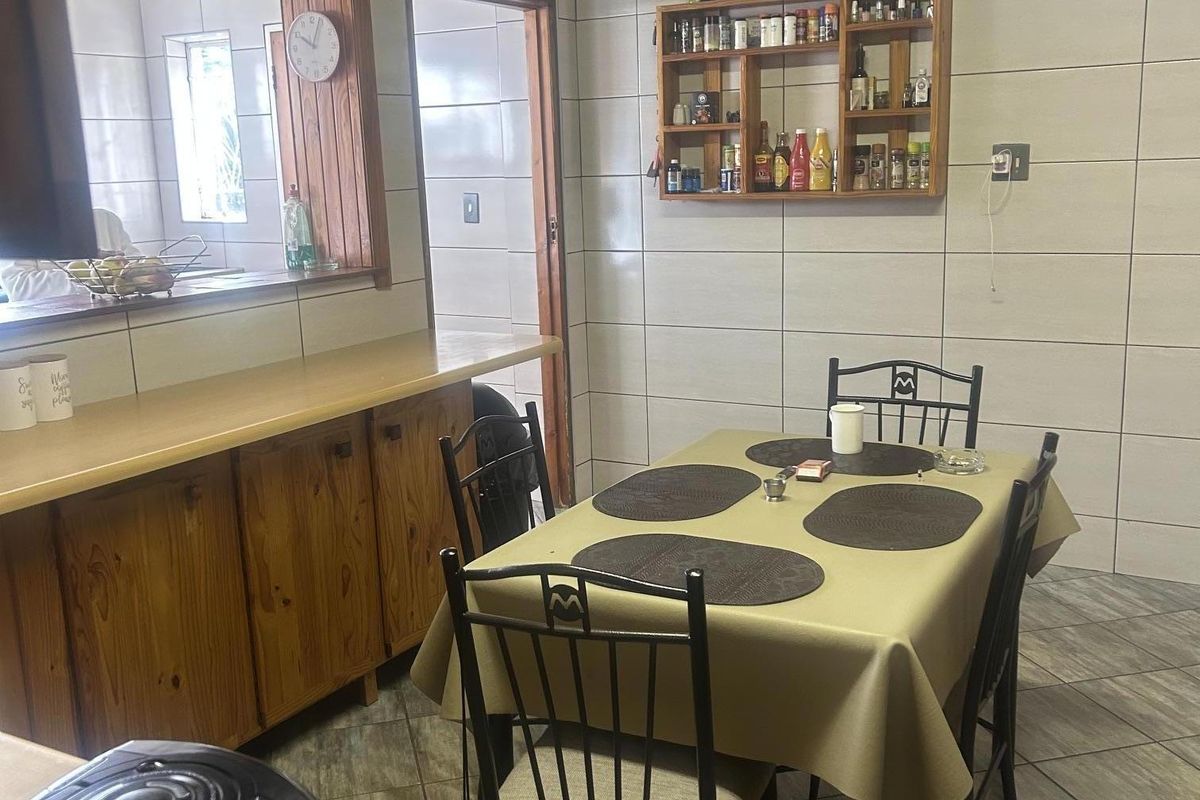 A functional kitchen area featuring tiled walls, timber ceiling, built-in wooden cabinetry, and a convenient serving hatch connecting to the adjacent space.
