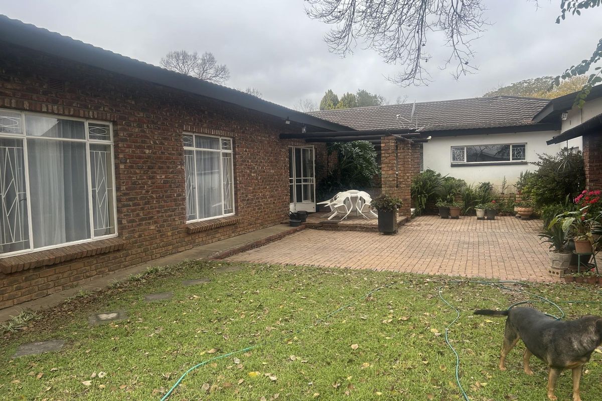 Rear view of the property featuring a brick facade, a paved patio area, and a garden space.
