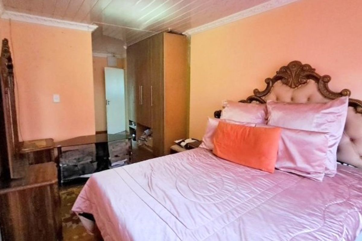 A bedroom featuring a built-in wardrobe and coved ceiling, currently finished with dated wall paint and ceiling panels.