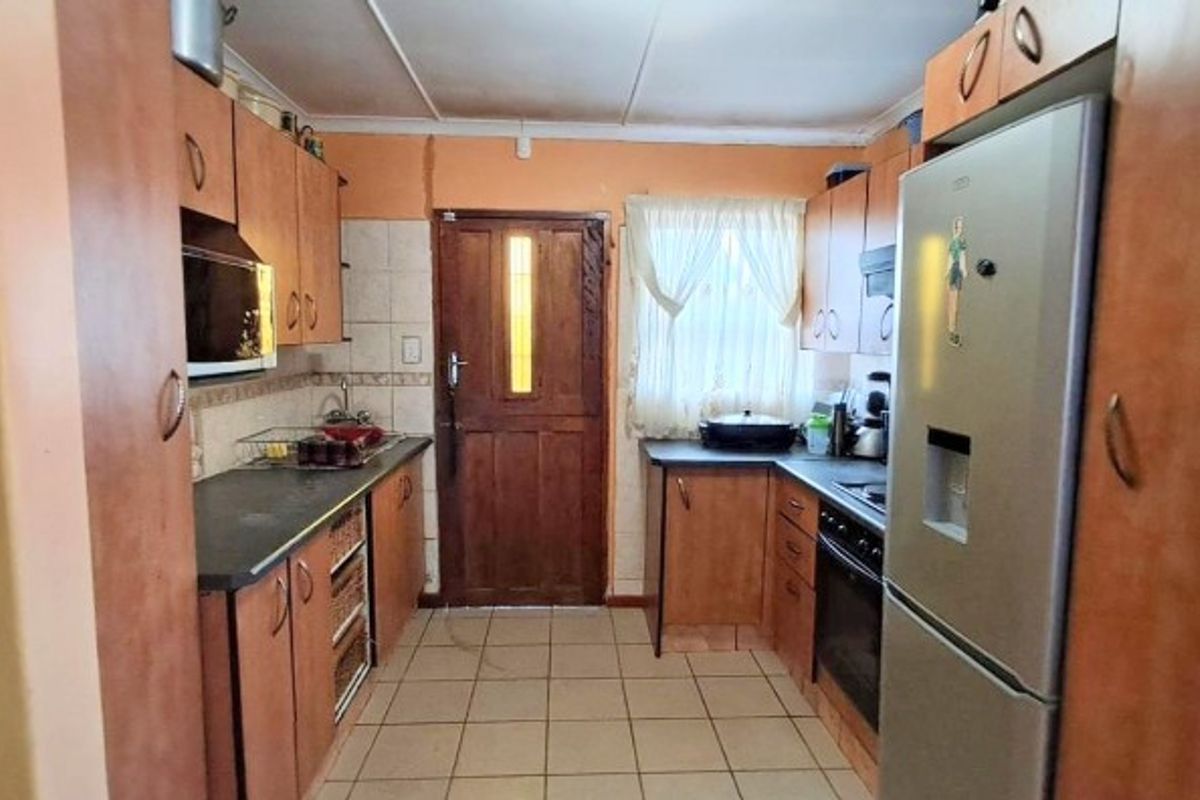 A functional kitchen featuring laminate cabinetry, built-in oven, hob, and tiled flooring, offering a practical layout with direct access to the exterior.